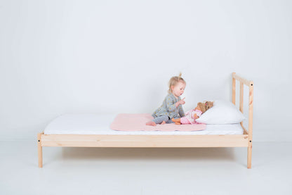 Toddler with Fuzzy Peach colour PeapodMat on a single bed