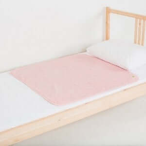 Medium PeapodMat on top of single bed in Fuzzy Peach colour