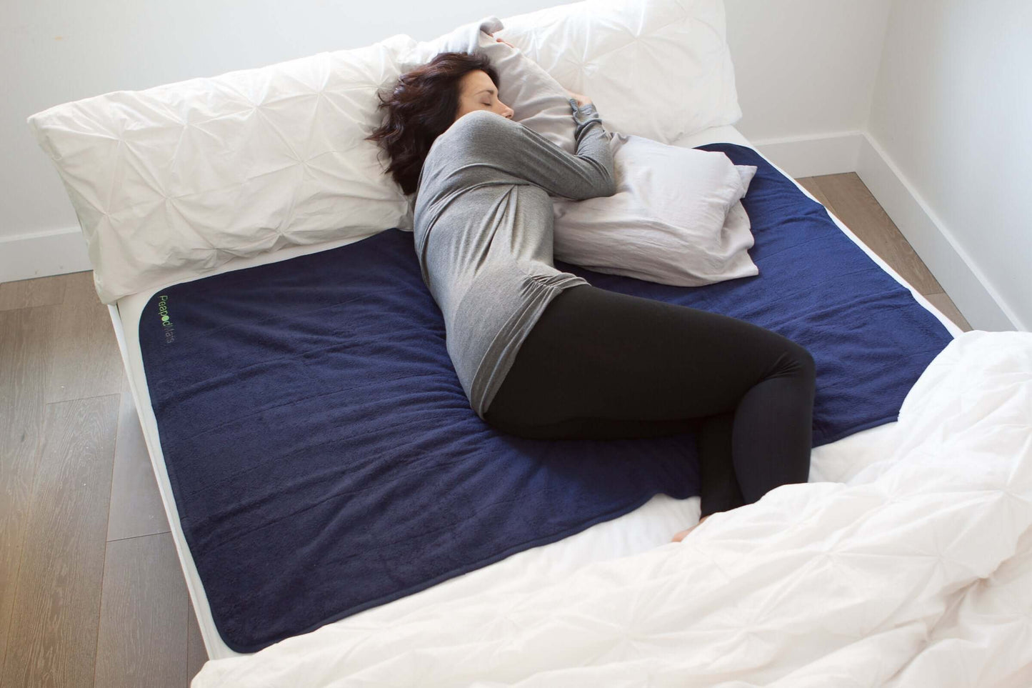 Woman sleeping with large PeapodMats horizontal across double bed
